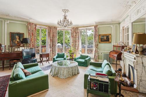 Elle comprend un salon doté d'un mobilier vert et d'une cheminée. dans l'établissement Appart haussmannien, à Paris