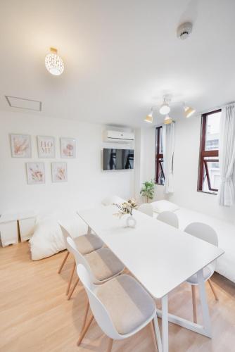 a white dining room with a white table and chairs at Tamagawa House 2BR in Osaka