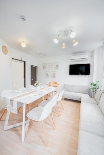 a white dining room with a white table and chairs at Tamagawa House 2BR in Osaka