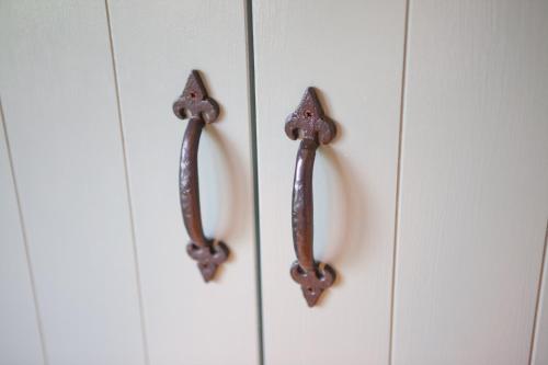 two wooden handles on a white cabinet at Barbara Shepherds Hut in Kent