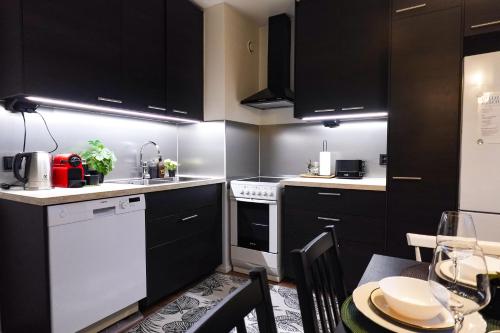 a kitchen with black and white cabinets and a table at Family Retreat Near Train and Kuusijärvi Lake in Vantaa