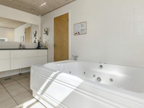 a white bathroom with a tub and a kitchen at 10 person holiday home in Væggerløse-By Traum in Marielyst