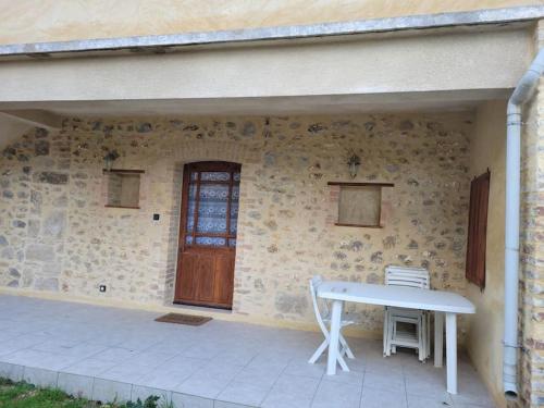 une table devant un bâtiment en pierre avec une porte dans l'établissement Logement proche station thermale, à Allegre Les Fumades