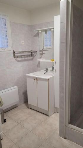 une salle de bain blanche avec un lavabo et une douche dans l'établissement Logement proche station thermale, à Allegre Les Fumades