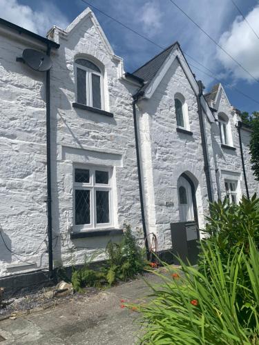 a white stone house with white windows and plants at Bodlondeb Holiday Let in Betws-y-coed