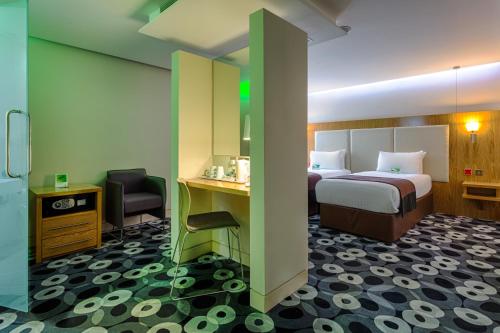 a hotel room with a bed and a desk and chair at Holiday Inn Sittingbourne by IHG in Sittingbourne
