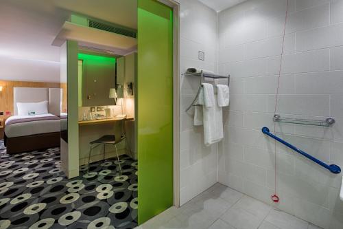 a bathroom with a green shower stall and a bed at Holiday Inn Sittingbourne by IHG in Sittingbourne