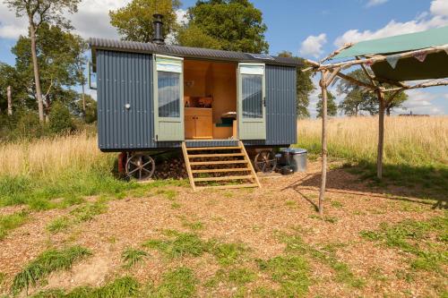 a blue tiny house sitting in a field at Barbara Shepherds Hut in Kent