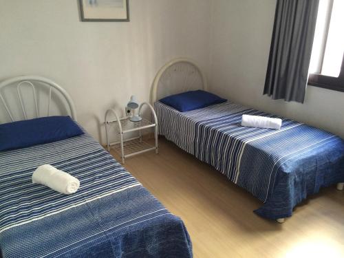 - 2 lits dans une chambre avec des draps bleus et blancs dans l'établissement Casa Germano 251, à Balneário Camboriú