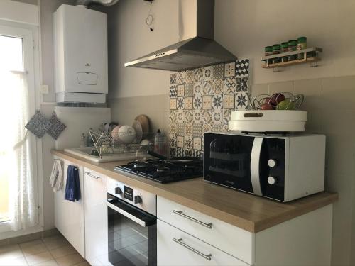 une cuisine avec un four micro-ondes au-dessus d'un comptoir dans l'établissement Appartement dans quartier calme avec petit jardin, à Montpellier