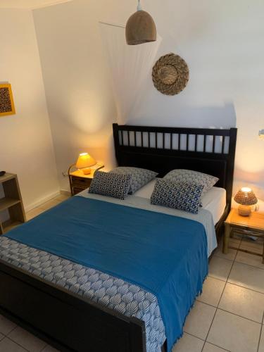 a bedroom with a bed with blue sheets and pillows at Les Manguiers in Deshaies