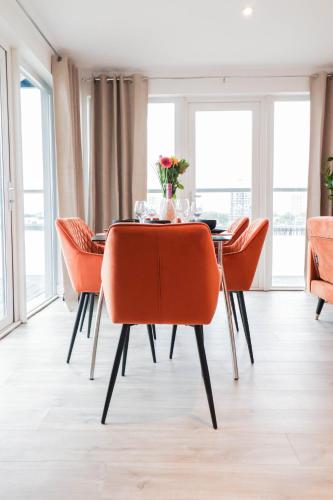 a dining room with orange chairs and a table at Spacious and Sunny Flat l River Balcony View ! in London
