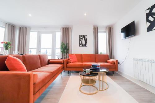 a living room with two orange couches and a table at Spacious and Sunny Flat l River Balcony View ! in London