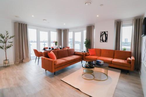 a living room with two orange couches and a table at Spacious and Sunny Flat l River Balcony View ! in London