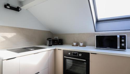 a small kitchen with a microwave and a stove at Cloud Stylish flat with jacuzzi near city center in Annecy