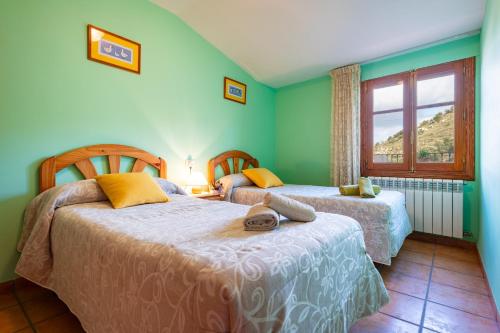 two beds in a room with green walls and a window at Casa Lino in Culla
