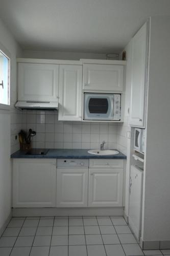 une cuisine avec des armoires blanches, un évier et un micro-ondes dans l'établissement Nice T3 with terrace and sea view, à Saint-Malo