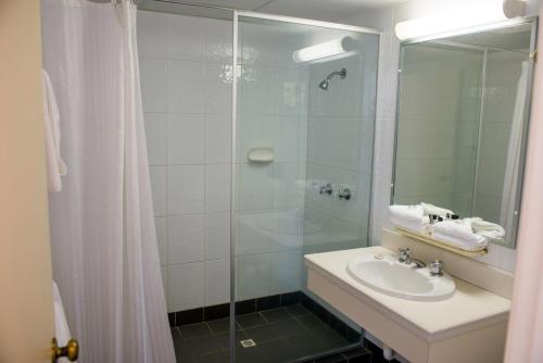 W łazience znajduje się umywalka i przeszklony prysznic. w obiekcie Alloggio Newcastle Beach w mieście Newcastle