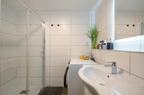 a white bathroom with a sink and a shower at Neue 4 Zi Küche Bad Parknähe in Neunkirchen