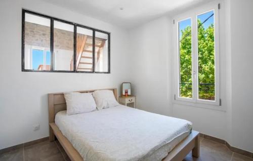 a white bedroom with a bed and two windows at Remarquable T3 proche plages in Carqueiranne