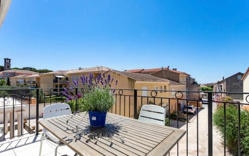 a wooden table with chairs and a potted plant on a balcony at Remarquable T3 proche plages in Carqueiranne