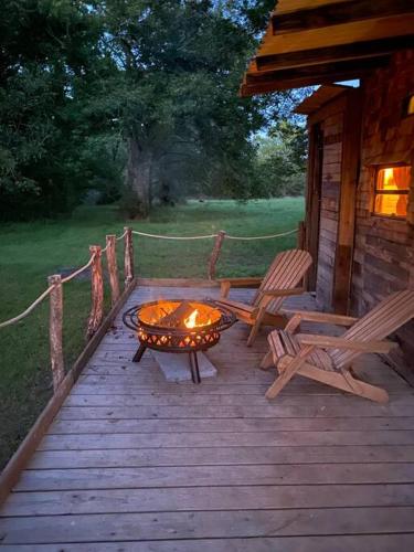 a wooden deck with a fire pit and two chairs at Pecan Grove Cabin in Huntsville