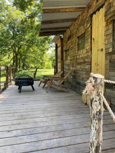a wooden porch of a log cabin with a grill at Pecan Grove Cabin in Huntsville