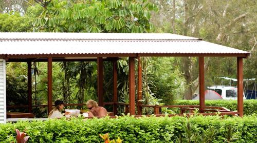 two people sitting at a table in a gazebo at Discovery Parks - Emerald Beach in Emerald Beach