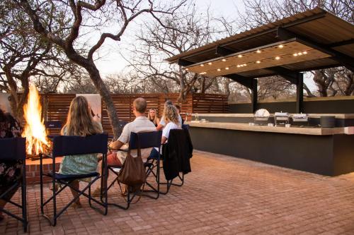 a group of people sitting around a fire pit at Aerotel in Hoedspruit