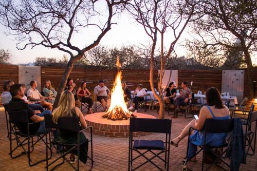 a group of people sitting around a fire pit at Aerotel in Hoedspruit