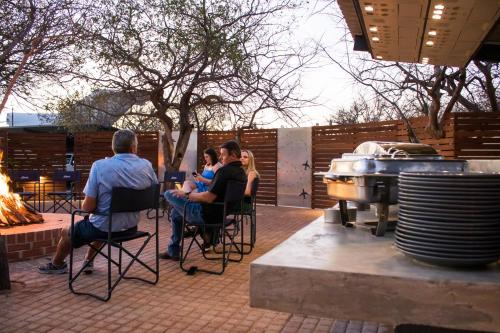 a group of people sitting in chairs around a grill at Aerotel in Hoedspruit
