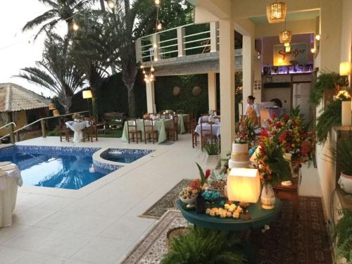a resort with a pool and a restaurant with a table at Pousada Bem Te Vi in Guarapari