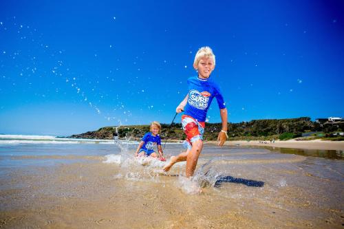 a young boy and a little girl playing on the beach at Discovery Parks - Emerald Beach in Emerald Beach