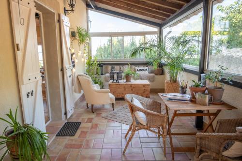 a conservatory with a table and chairs and plants at Les Deux Petits Pois in Fanjeaux