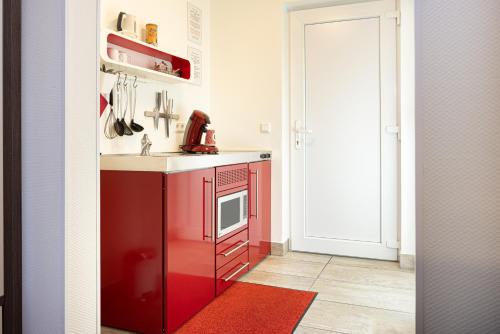 a red kitchen with a sink and a microwave at Hotel Gasthof Handewitt in Handewitt