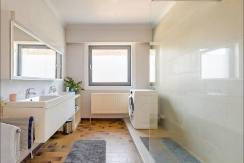 a white bathroom with a sink and a tub at Appartement224 in Grimbergen