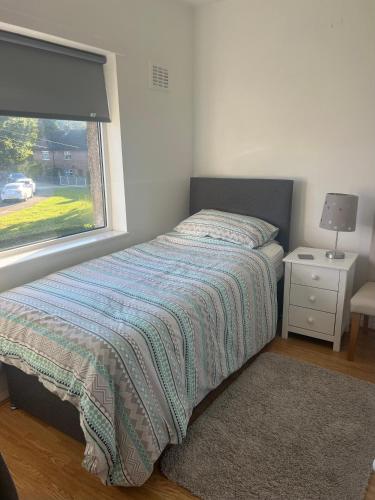 a bedroom with a bed with a window and a nightstand at Cozy 2 BDRM Apartment Nr the World Heritage Site of Saltaire in Saltaire