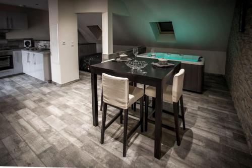 une cuisine avec une table noire et deux chaises blanches dans l'établissement VIP 2 Loft avec spa privatif à 10 min de Dijon, à Fauverney