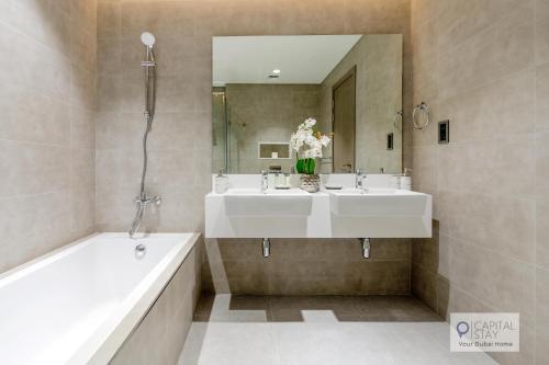 a bathroom with two sinks and a tub and a mirror at 2 Bed Apt in District One Dubai - Lagoon Views in Dubai