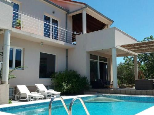 a house with a swimming pool in front of a house at Apartments Villa Dona -Two Bedroom Apartment with Shared Swimming Pool in Vela Luka