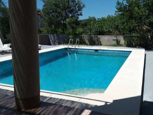 a swimming pool with blue water in a yard at Apartments Villa Dona -Two Bedroom Apartment with Shared Swimming Pool in Vela Luka