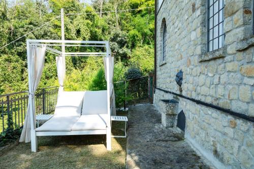 a white swing on a balcony with a stone wall at Villa Allegra Apartments in The Nature in Pozzolgroppo