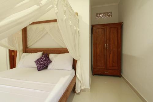 a bedroom with a canopy bed and a wooden cabinet at Suryadina Guest House in Ubud