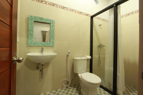 a bathroom with a toilet and a sink and a shower at Suryadina Guest House in Ubud