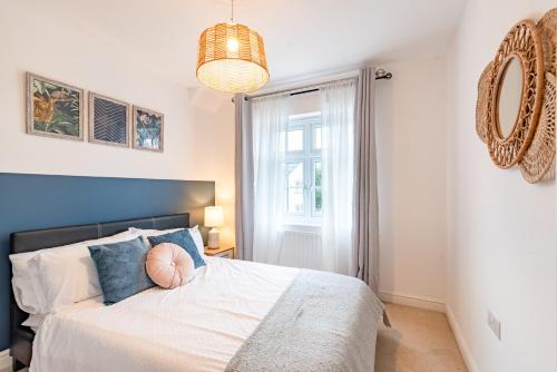 Un dormitorio con una cama con cabecero azul y una ventana. en Convenient & cosy 3 bed house, en Newport
