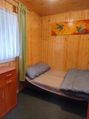 two beds in a wooden room with a window at Domek nad jeziorem -Mazury- Linia Brzegowa in Piotrowice
