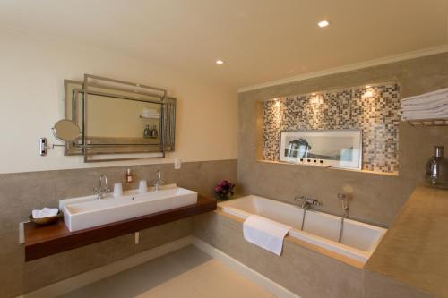 ein Badezimmer mit Waschbecken, Badewanne und Spiegel in der Unterkunft Villa Reynaert in Opoeteren