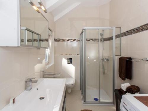 a white bathroom with a shower and a sink at Mali Skoj Apartment - Two-Bedroom Apartment with Sea View in Suđurađ