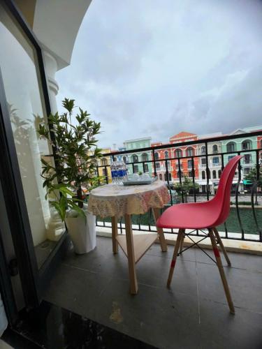 a table and a red chair on a balcony at Thiên Ý Homestay in Phu Quoc