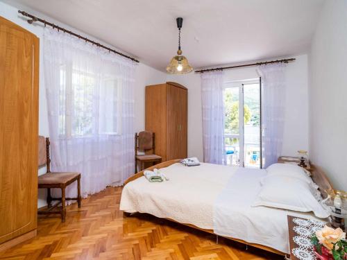 a bedroom with a white bed and a window at Apartments Zarac - One Bedroom Apartment with Balcony and Sea View Milanka in Zaton